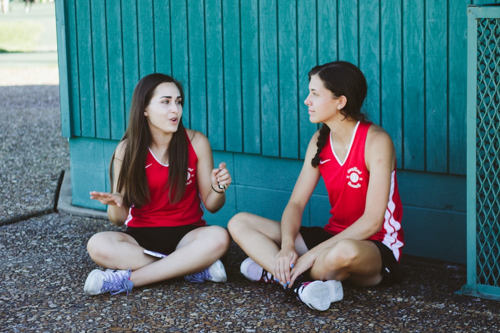 woman in red Nike tank top sitting beside woman in red tank top