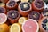 An assortment of fresh fruits featuring prominently cut pomegranates with ruby red seeds glistening, surrounded by slices and whole citrus fruits like oranges and grapefruits. The vibrant colors of the fruits create an appealing and fresh presentation.