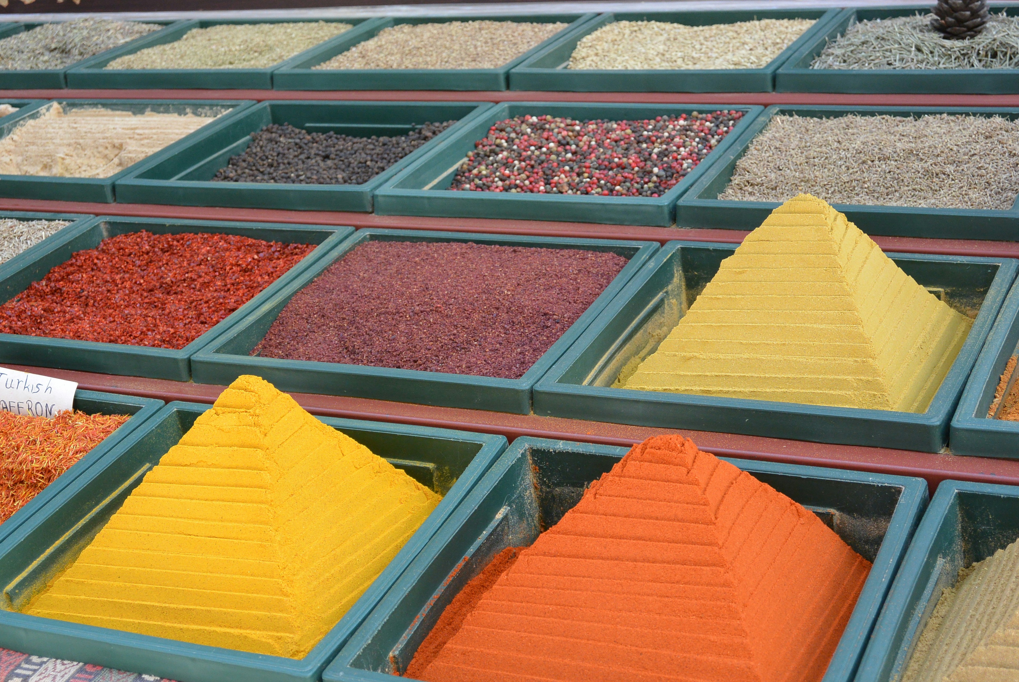Street vendor arranging pyramids of colorful spices at market, hands moving with practiced grace