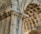 Detailed architectural elements of a historic stone structure featuring ornate carvings and intricate designs. The stonework includes decorative patterns on the arches and pillars, showcasing the craftsmanship of classical architecture.