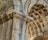 Detailed architectural elements of a historic stone structure featuring ornate carvings and intricate designs. The stonework includes decorative patterns on the arches and pillars, showcasing the craftsmanship of classical architecture.