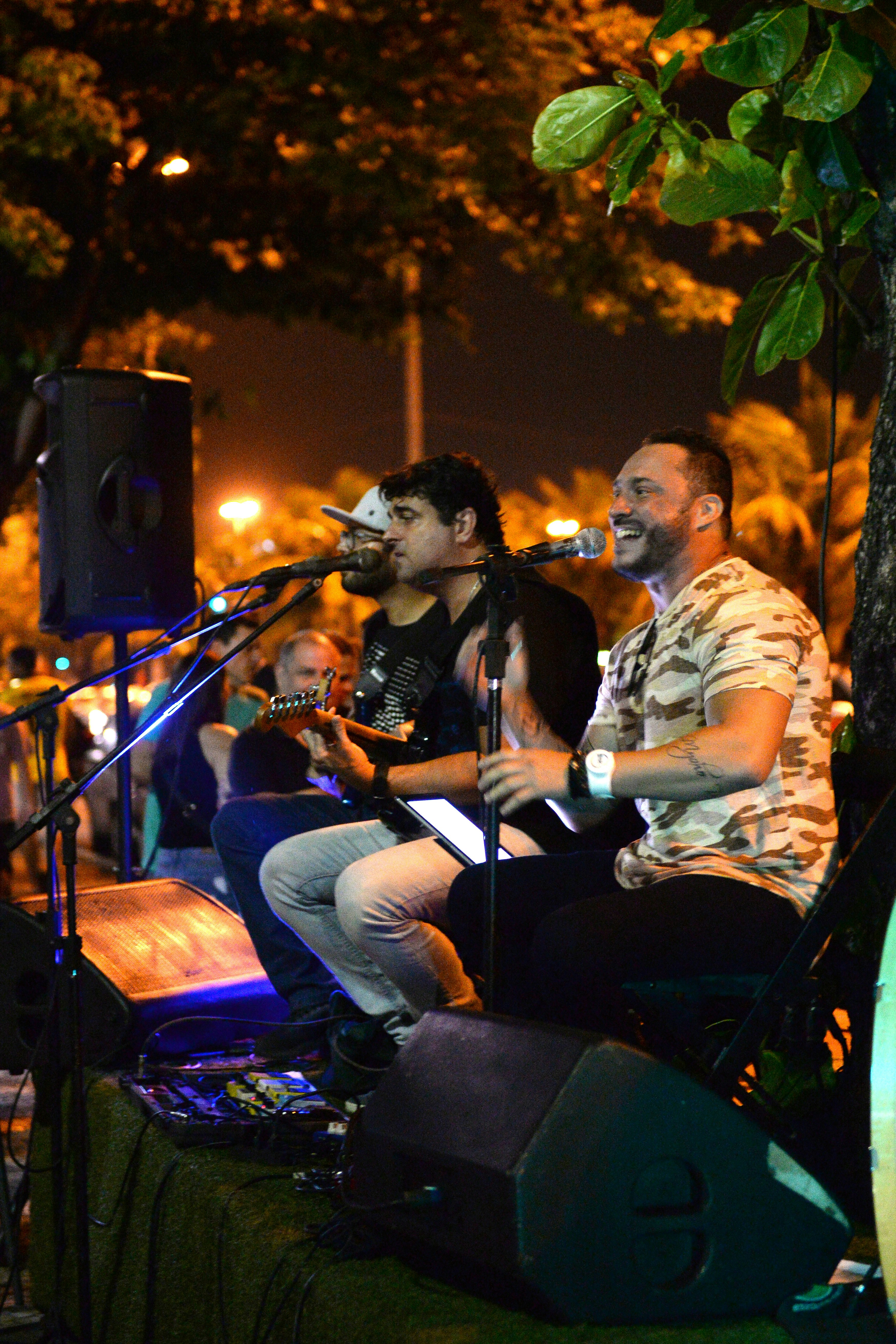 Músico tocando guitarra em ambiente ao ar livre com iluminação quente ao entardecer