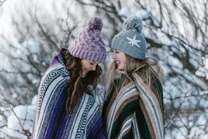 two women in multicolored striped blanket standing near tree