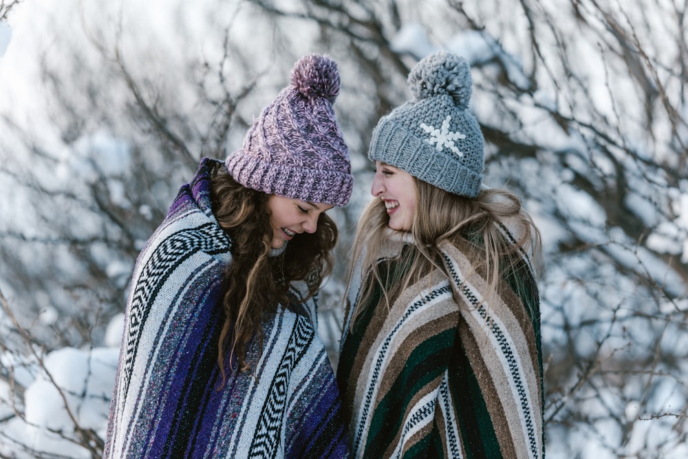 Due donne in coperta a righe multicolori in piedi vicino all'albero