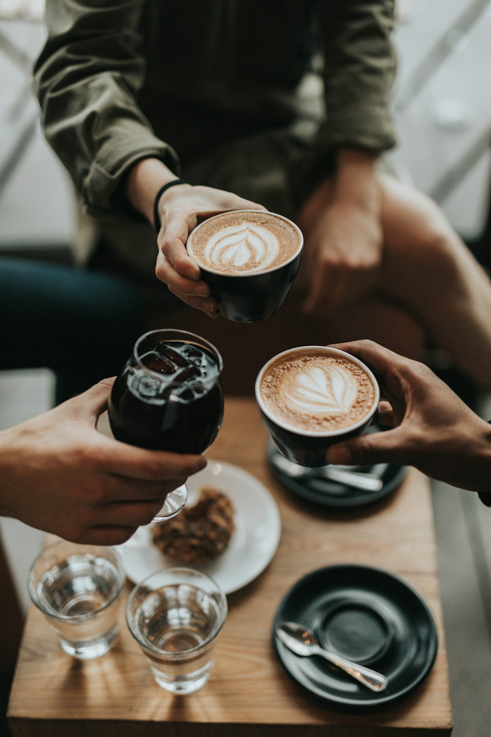 three person holding mug and glass with beverage inside