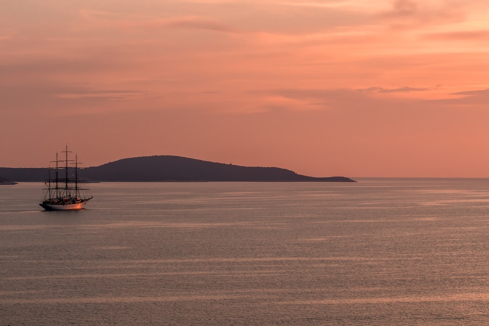 photo of black sailing boat on body of water