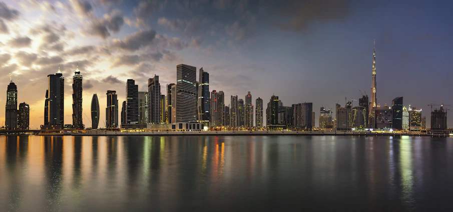A panoramic view of the UAE skyline at dusk with glowing city lights and modern skyscrapers.