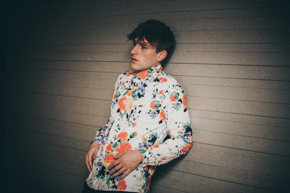 man wearing floral dress shirt leaning on wall