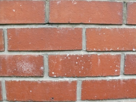 Before and after images showing a renovated brick wall with fresh mortar and clean edges.
