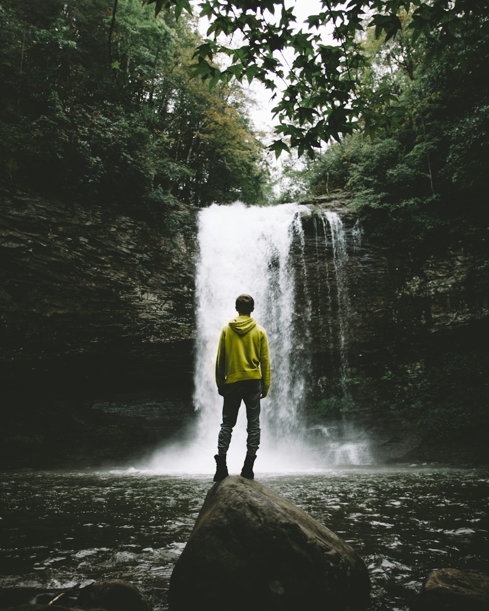 man standing on rock looking at waterfalls
