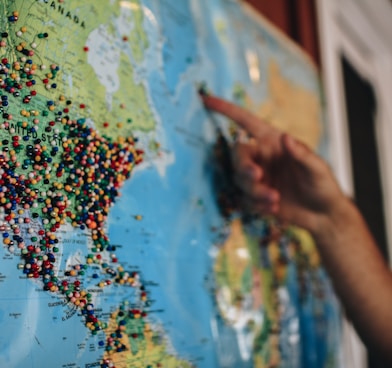 a person pointing at a map with pins on it