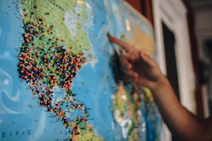 a person pointing at a map with pins on it