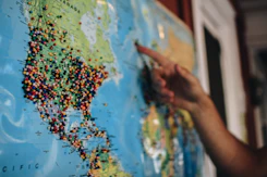 a person pointing at a map with pins on it