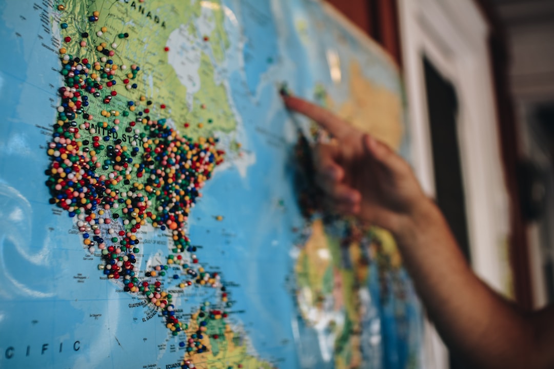 a person pointing at a map with pins on it
