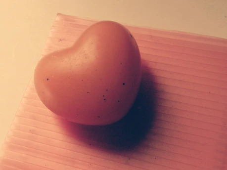 Close-up of a heart-shaped p1 device resting on a wooden table with soft natural light.