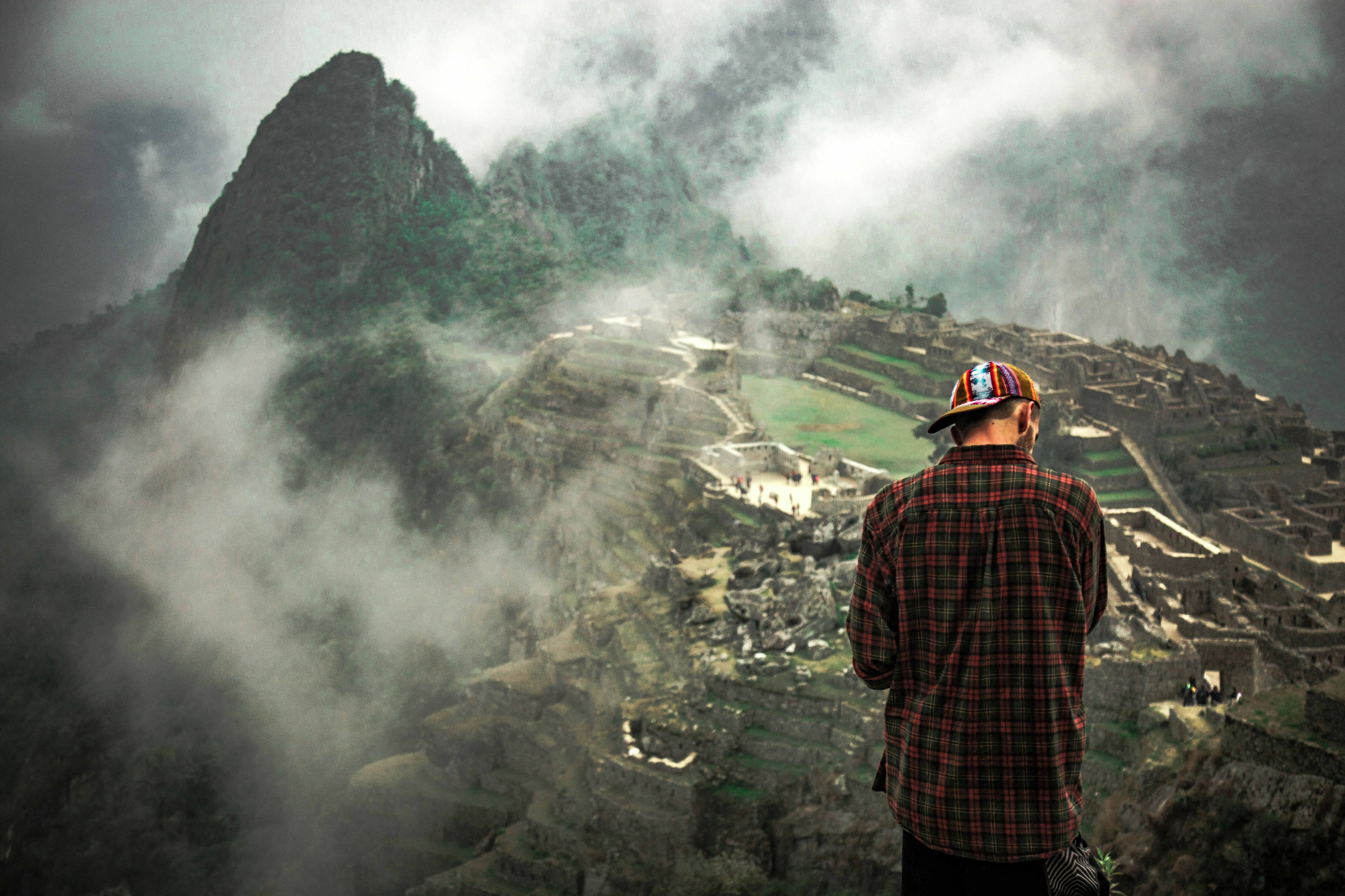 man standing on cliff facing mountain rice terraces