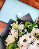 A beautifully arranged wedding bouquet resting beside a glowing laptop screen.