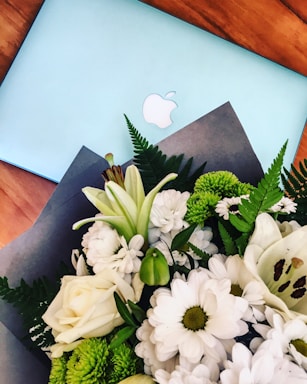 A vibrant bouquet of fresh flowers resting next to a laptop showing the goviaflowers dashboard.