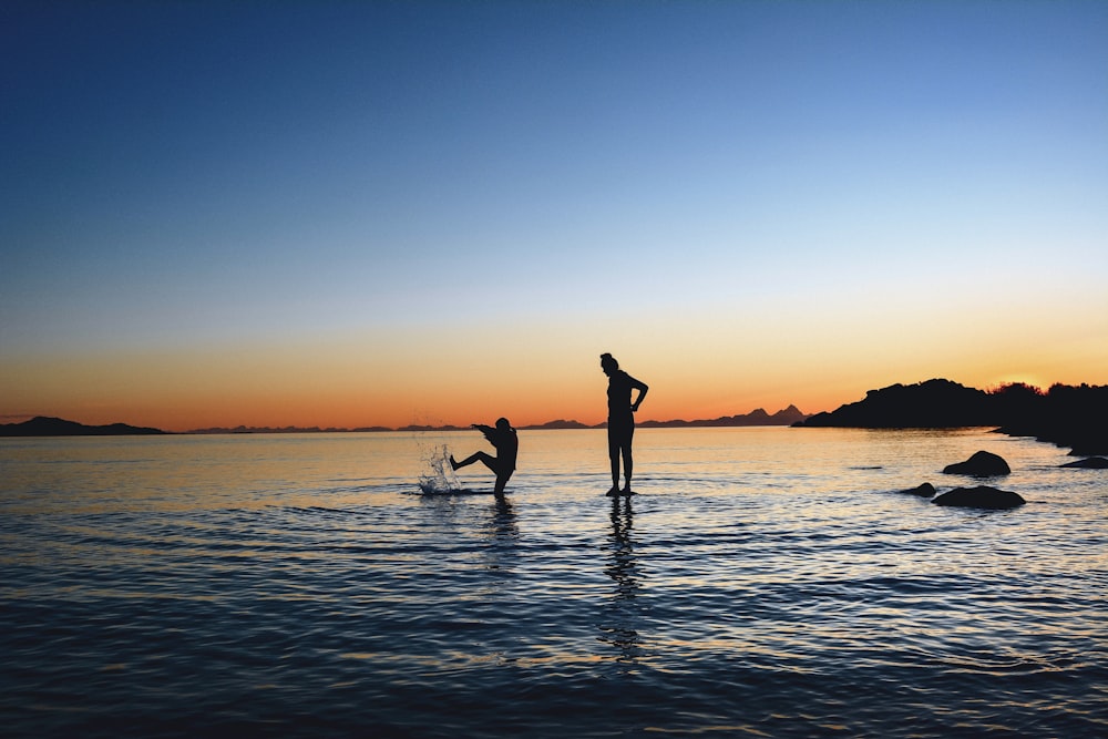 silhouette photography of two persons on body of water