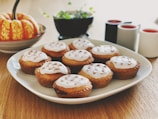 A smiling home baker arranging freshly baked cupcakes on a rustic wooden table.