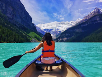 Woman kayaking on a mountain lake during an outdoor travel adventure.