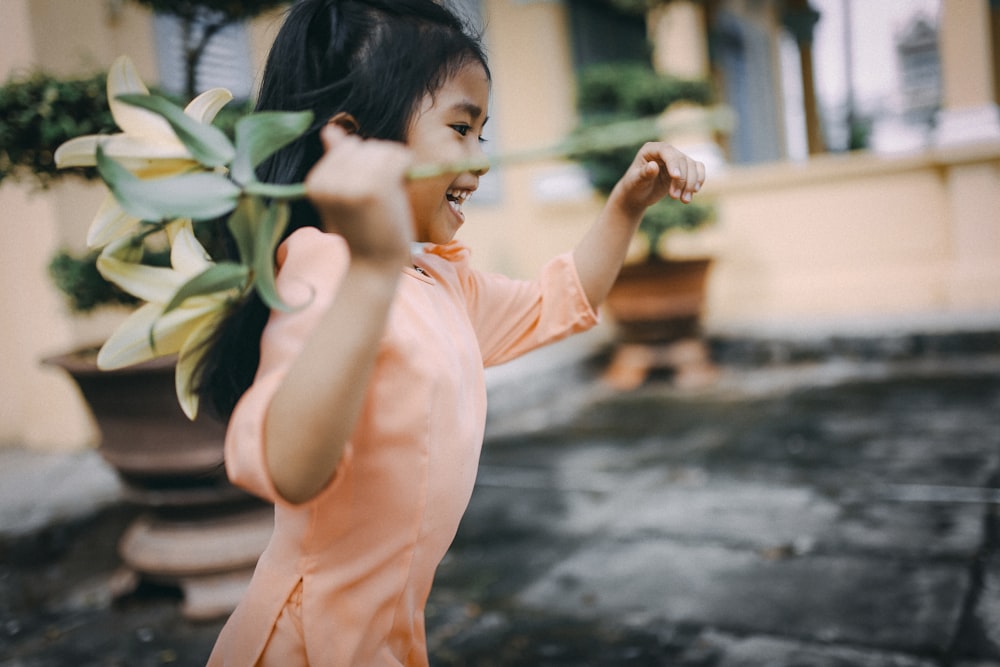 menina segurando uma flor amarela enquanto corre