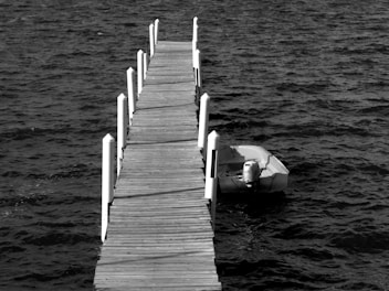 A wooden dock stretching into West Fox Lake with a pontoon boat tied up.