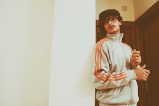 man wearing Adidas jacket leaning on wall