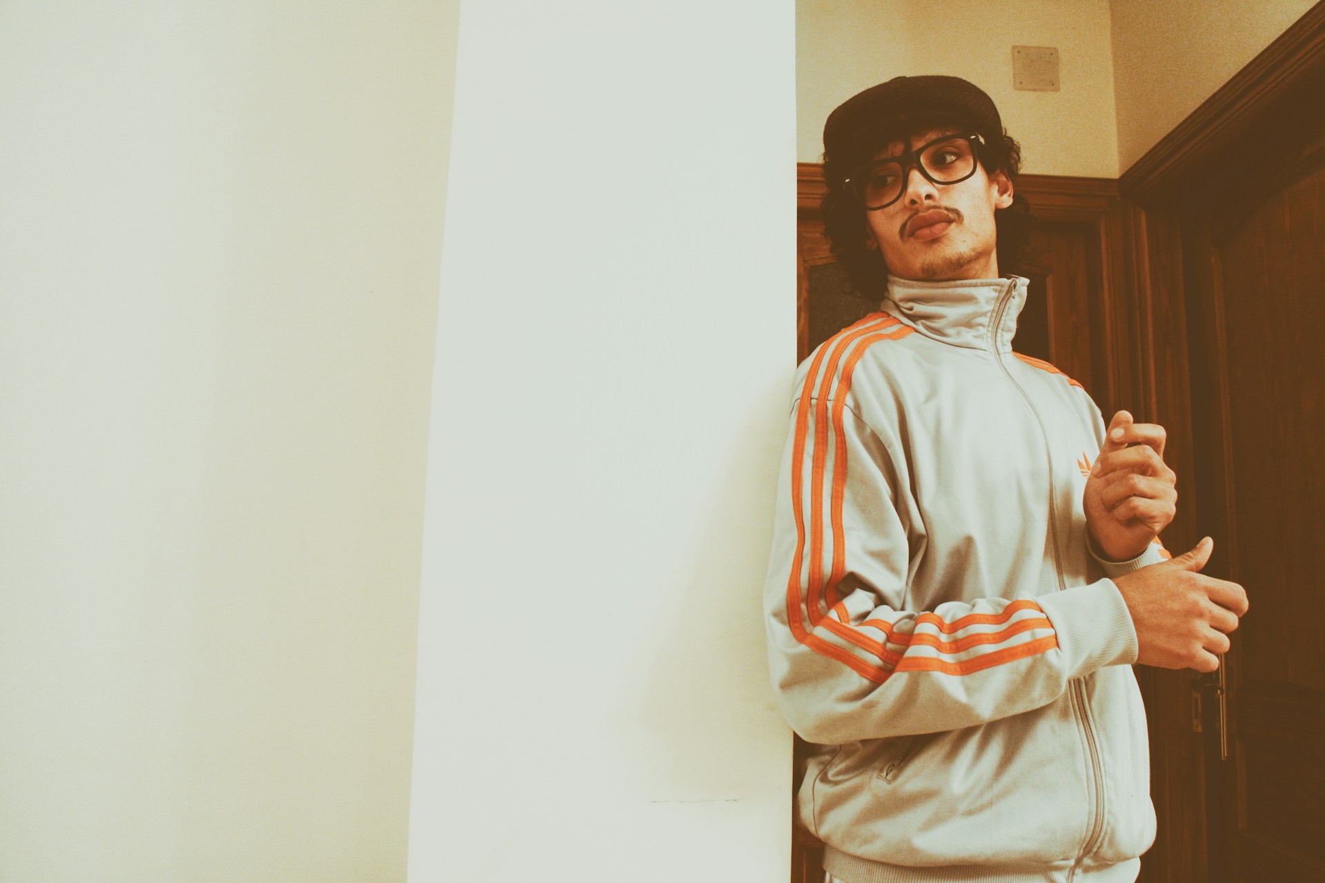 man wearing Adidas jacket leaning on wall