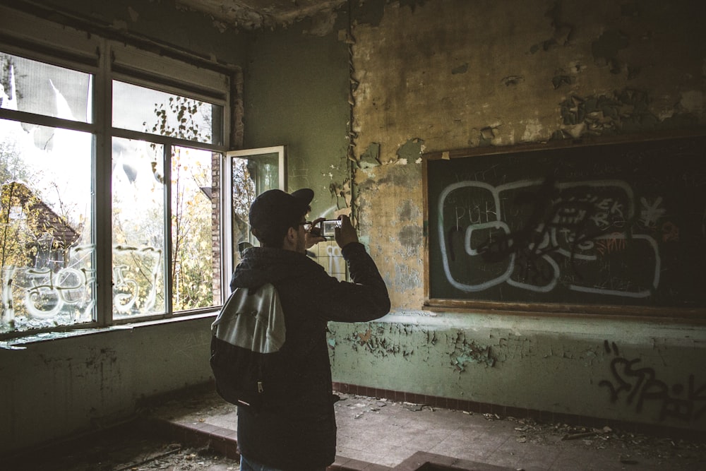 man talking a picture of chalkboard using smartphone inside classroom during day