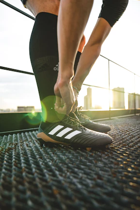 Young athlete tying cleats decorated with vibrant itrupo strikes, ready for game day energy.