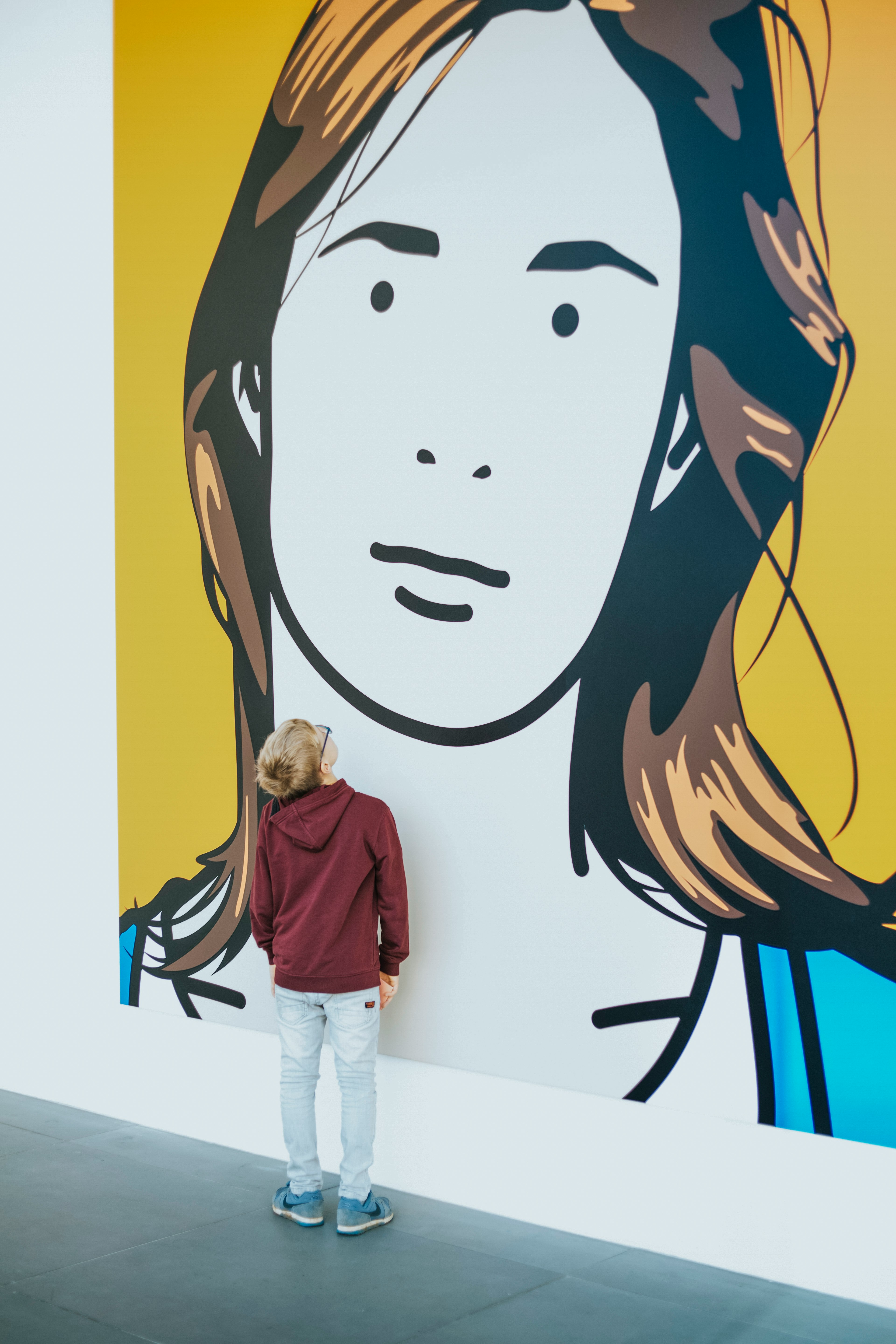 boy standing and facing woman wall painting