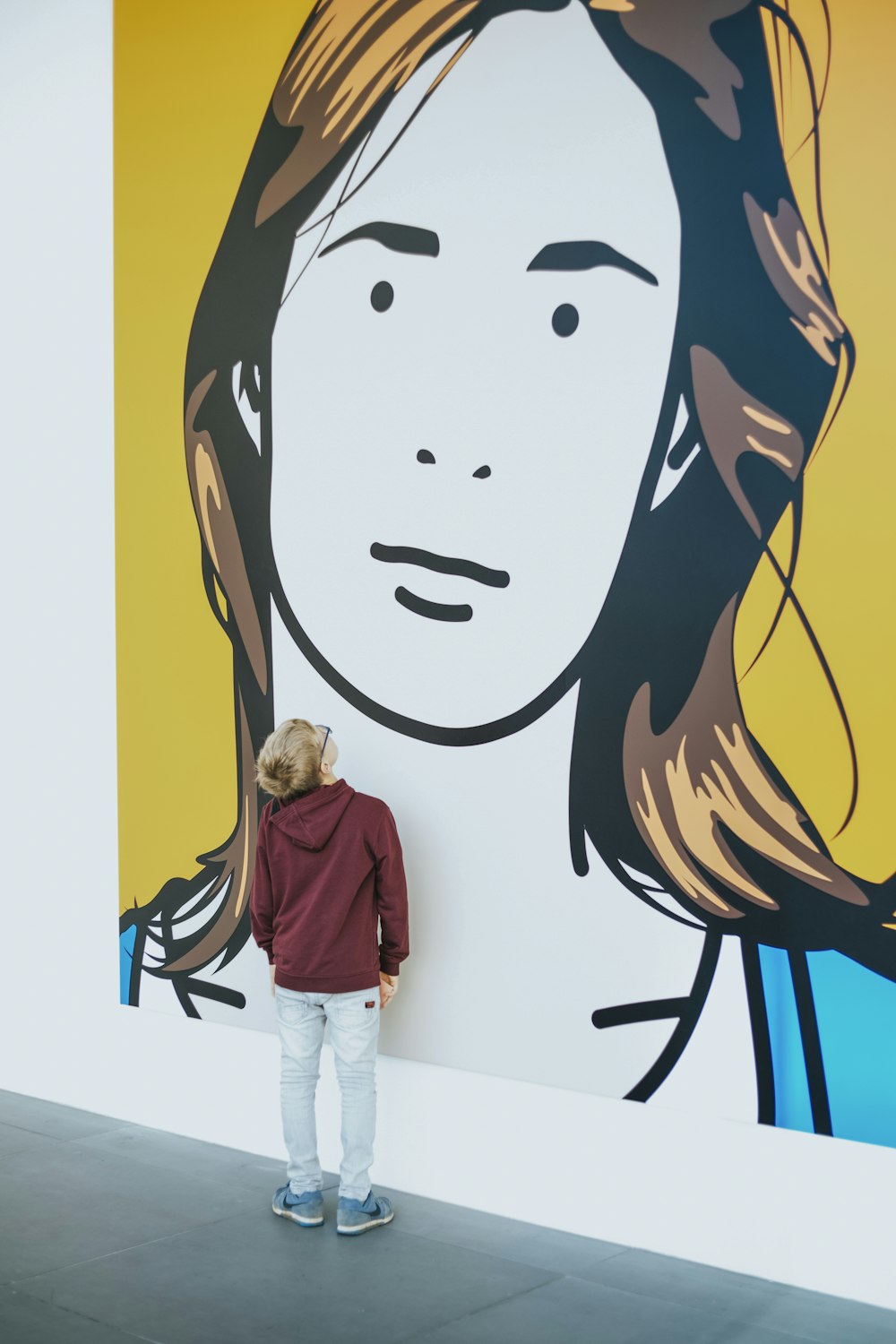 Niño de pie y frente a la pintura de la pared de la mujer