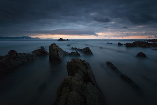 rock formations on body of water under cloudy sky in Barrika Spain