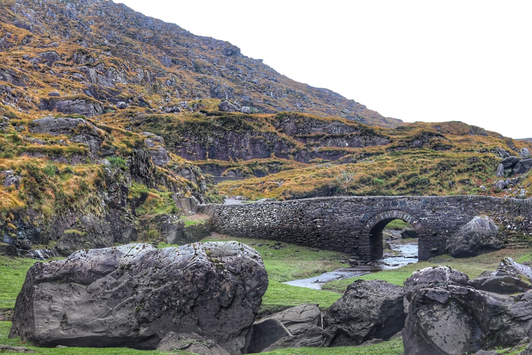 gray concrete bridge beside a mountain,