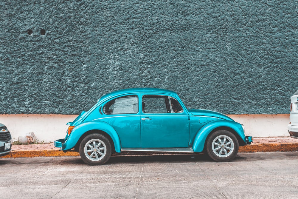 teal Volkswagen Beetle car parked beside sidewalk