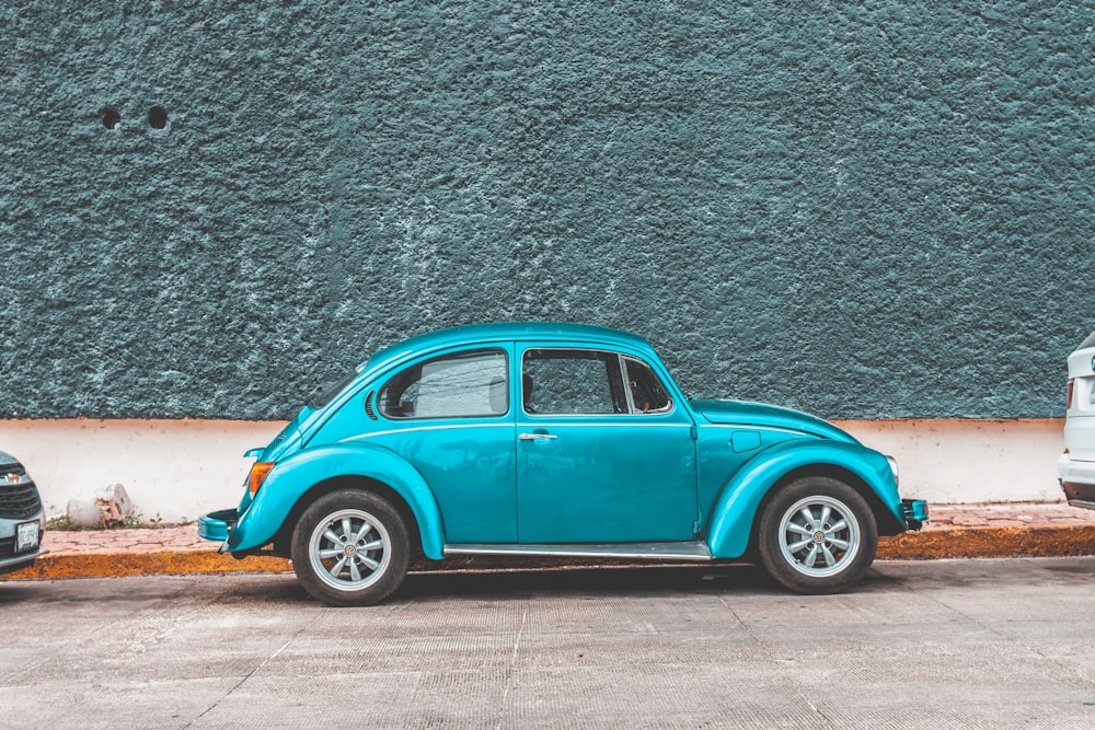 Coche Volkswagen Beetle verde azulado aparcado junto a la acera