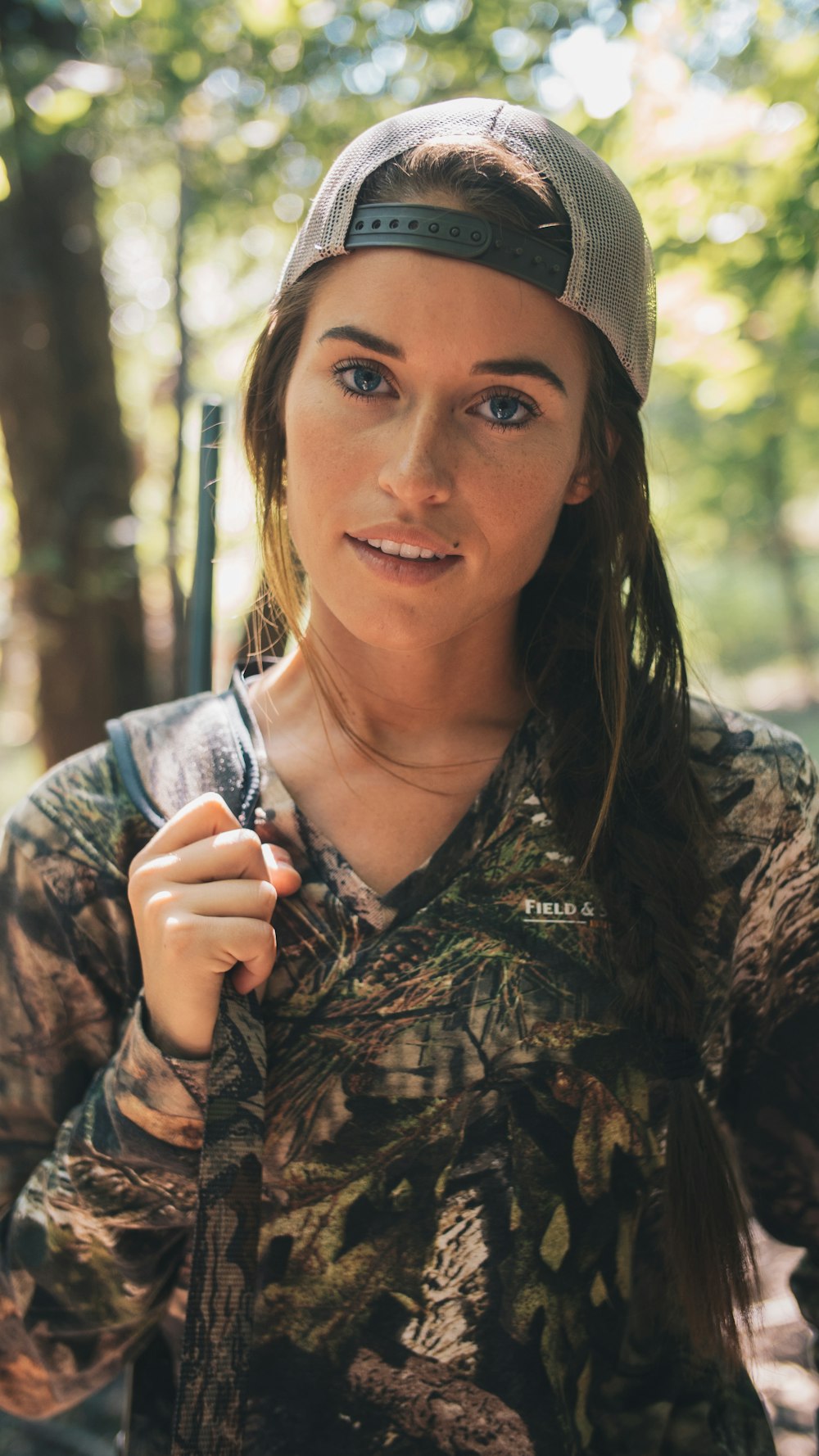 woman wearing realistic camouflage top and carrying rifle