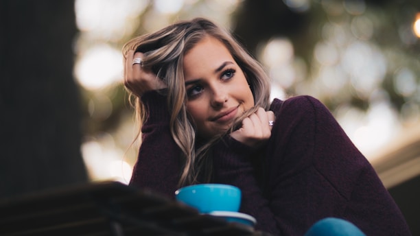 woman in purple long-sleeved top holding her hair