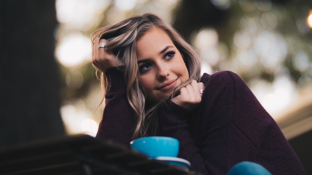 woman in purple long-sleeved top holding her hair