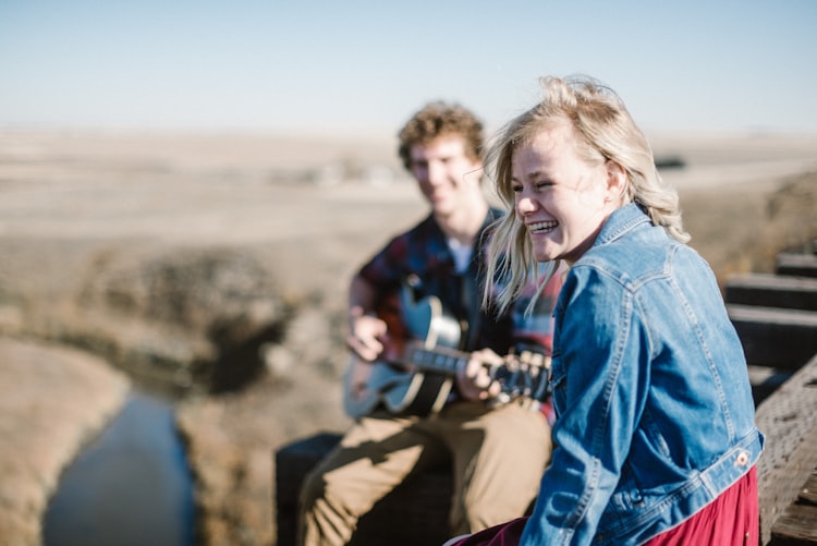 guy sitting with a girl and playing guitar