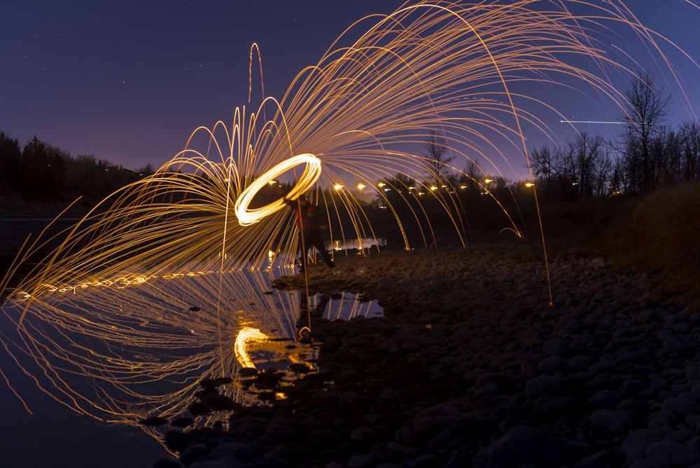 time-lapse photography of person holding lighted steel wool at night
