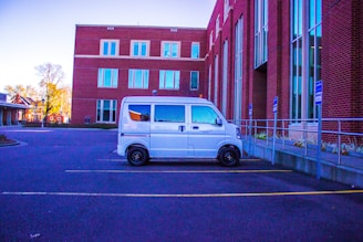A delivery van parked in front of a modern office building.