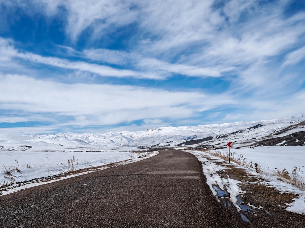 estrada de asfalto preto ao lado do campo coberto de neve