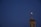 A mosque dome with a crescent moon symbol is lit up against a dark blue evening sky. A drone is seen flying above, its silhouette barely visible.