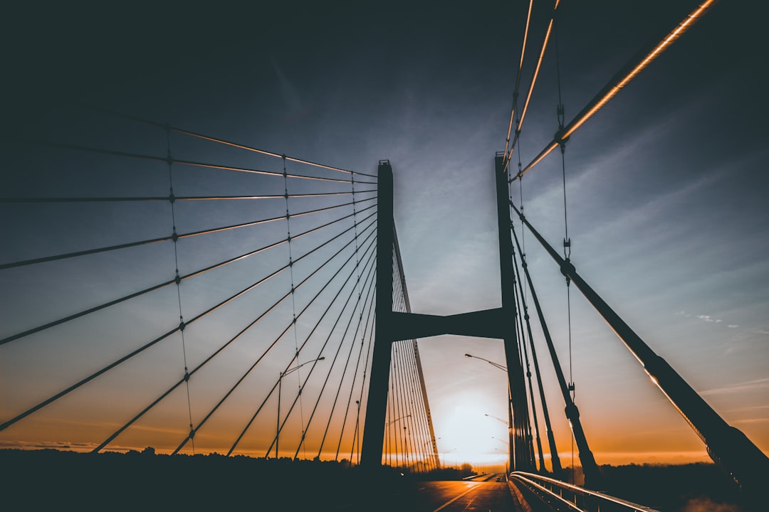 silhouette photograph of bridge under stratus clouds