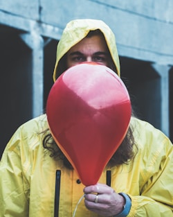 person on raincoat holding red balloon
