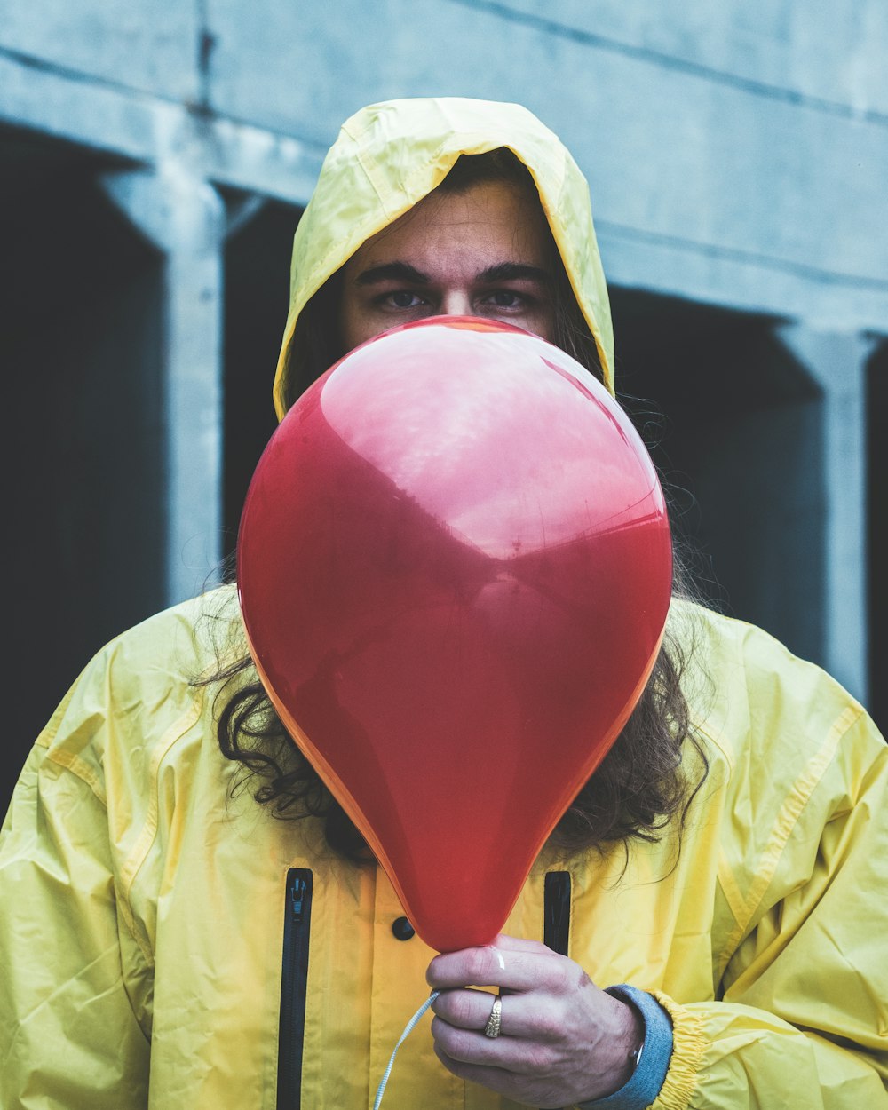 pessoa na capa de chuva segurando balão vermelho