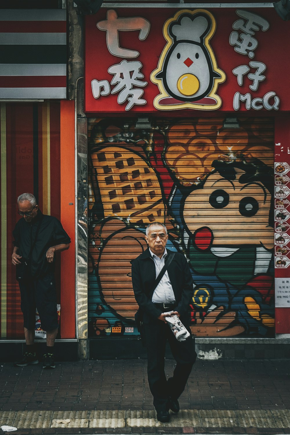 Mann steht auf der Straße vor rotem Laden