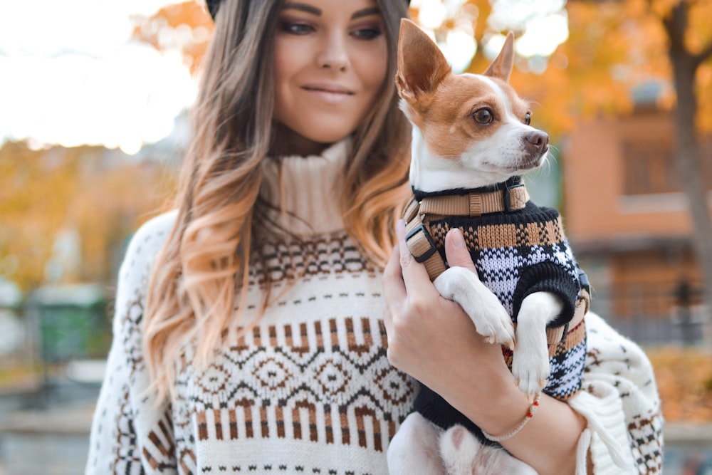 Mujer sosteniendo perro blanco y marrón